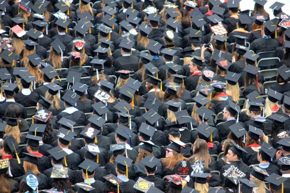 college students at graduation in black caps and gowns