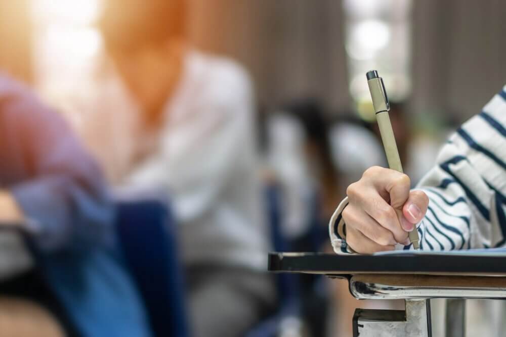 Students writing with pen, filling out an exam
