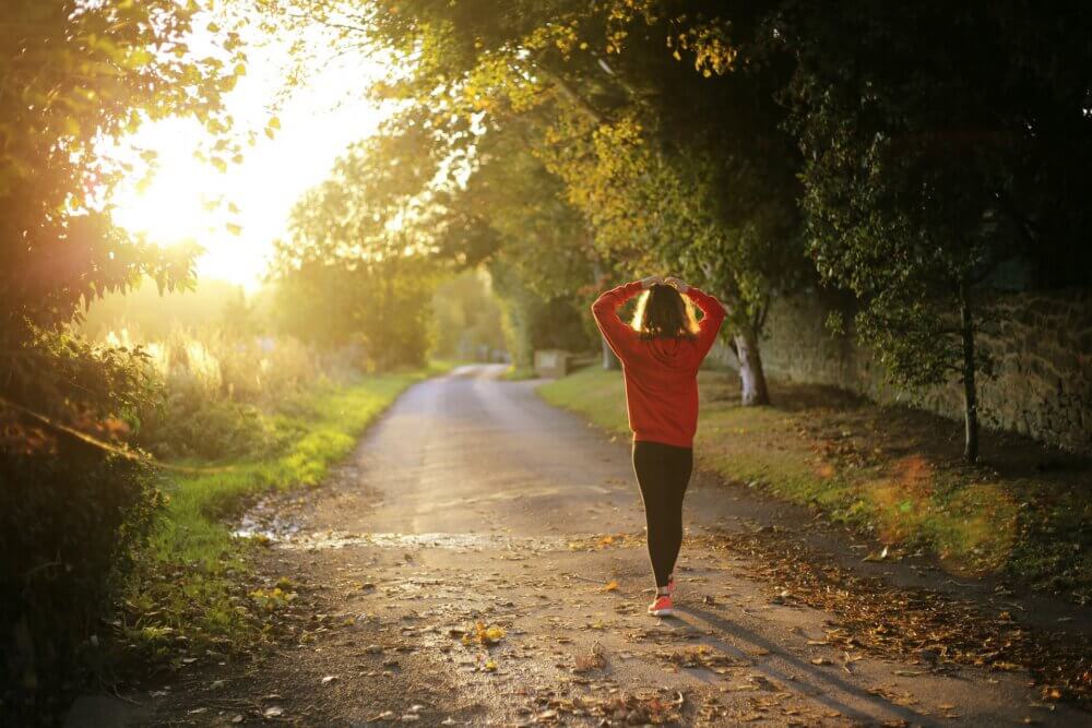 woman in red jacket and leggings walking on a dirt trail