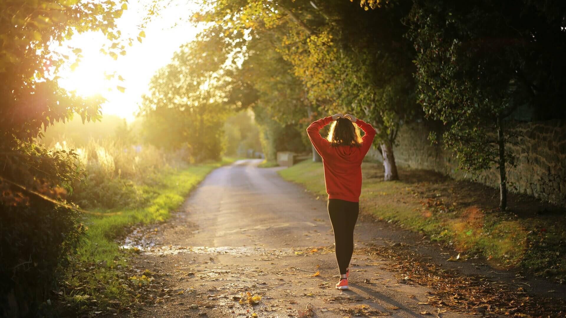 woman in red jacket and leggings walking on a dirt trail