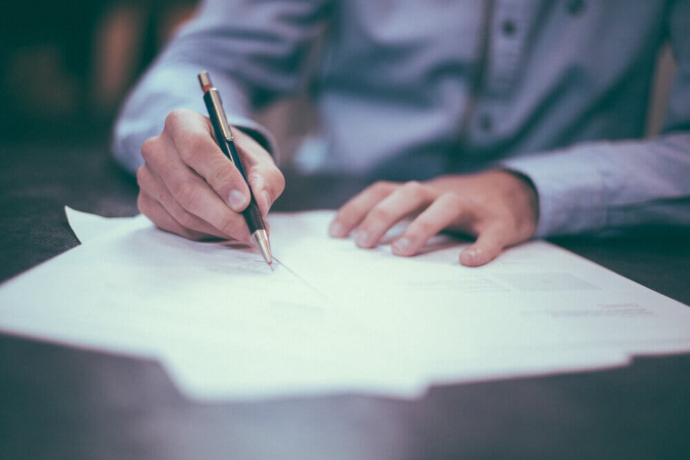 person writing with pen on paper