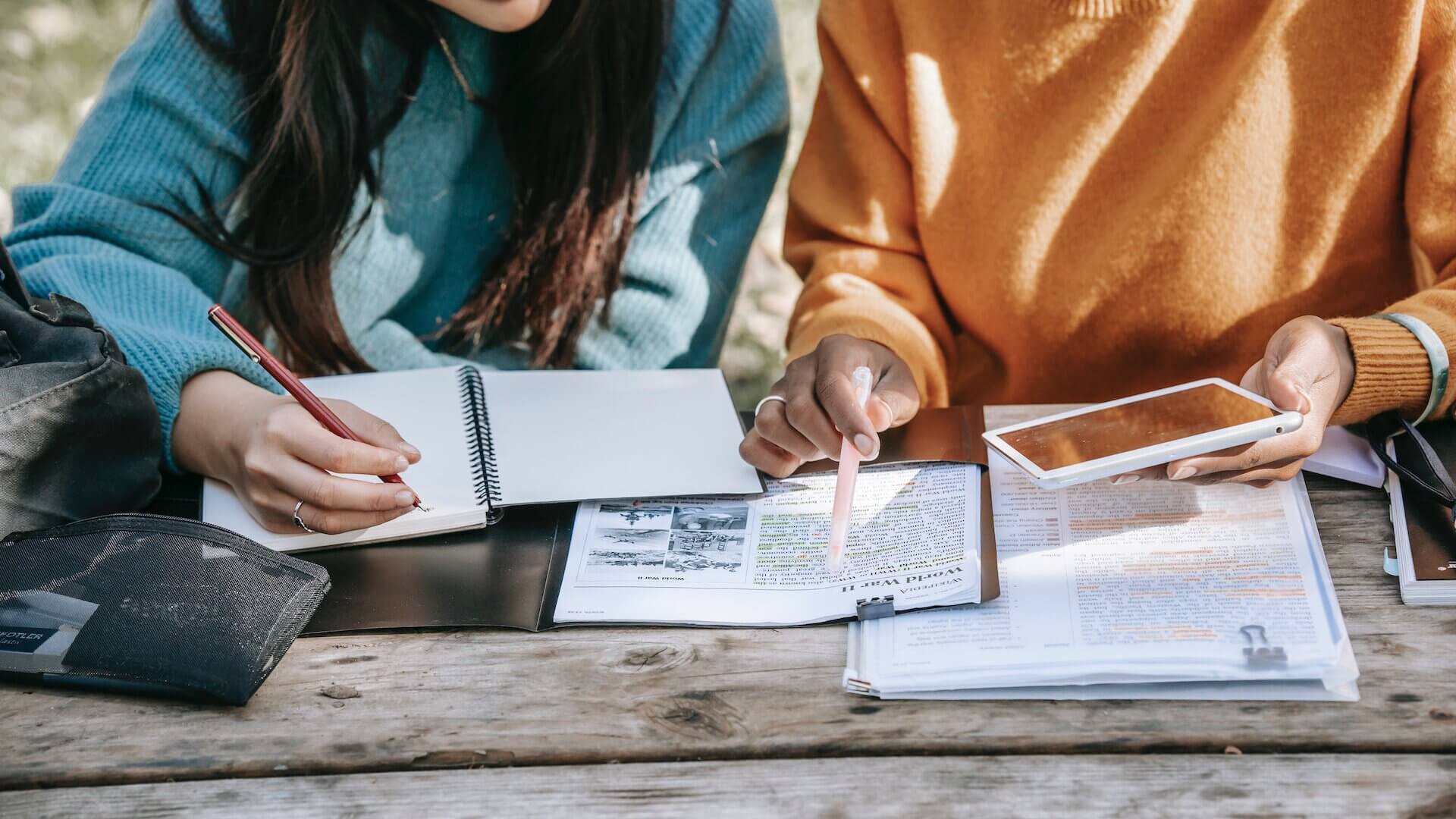two women in blue and white sweaters comparing notes on paper