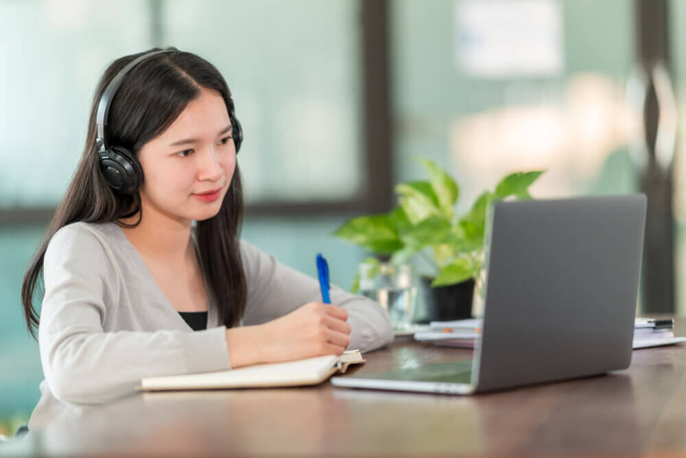 A young Asian university student wearing headphones to study online at home,During the time of the virus outbreak and did not attend university.