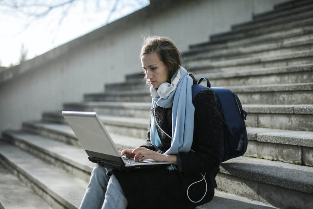 person sitting on stairs typing on computer