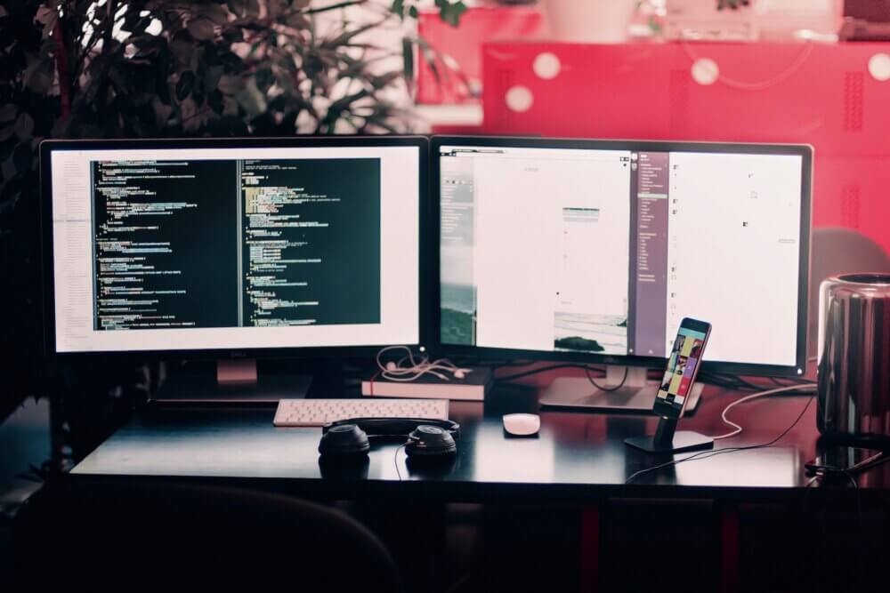 two computer monitors turned on sitting on a black desk