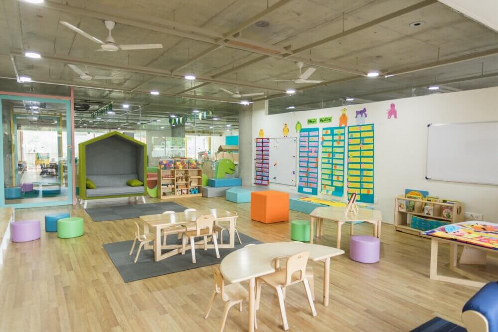 child day care room with wooden tables and chairs and colorful letter boards