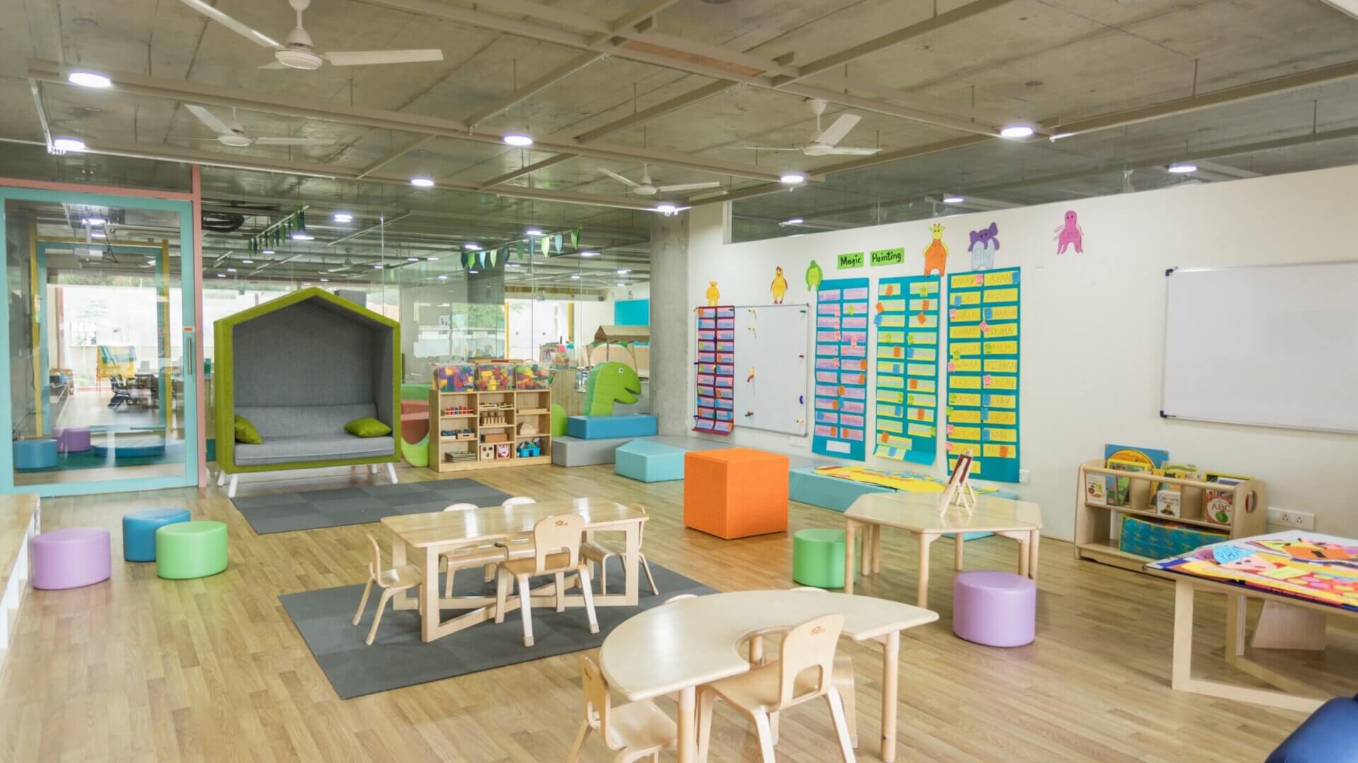 child day care room with wooden tables and chairs and colorful letter boards