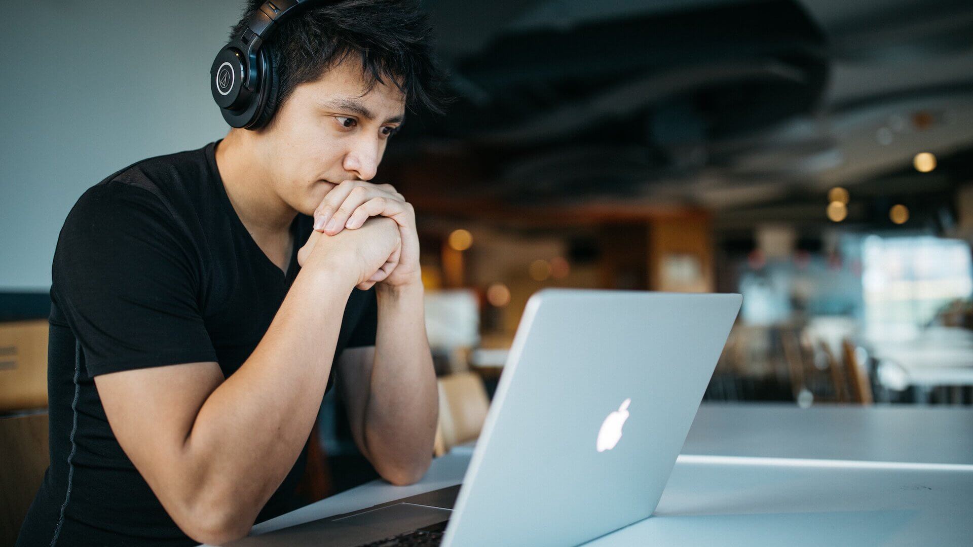 Frustrated student sitting at desk with open Mackbook and headphones on