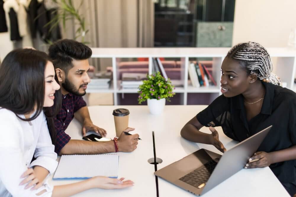 Young female executive presenting her ideas to colleagues in a meeting. Young people discussing work at desk in office.