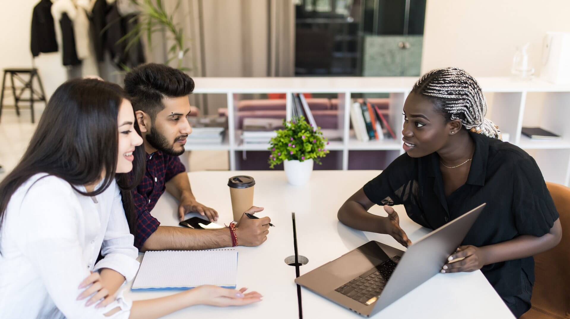 Young female executive presenting her ideas to colleagues in a meeting. Young people discussing work at desk in office.