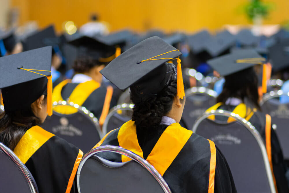 Rear view and soft selective focus of the graduates in the graduation commencement ceremony recieving diploma degree certificate.