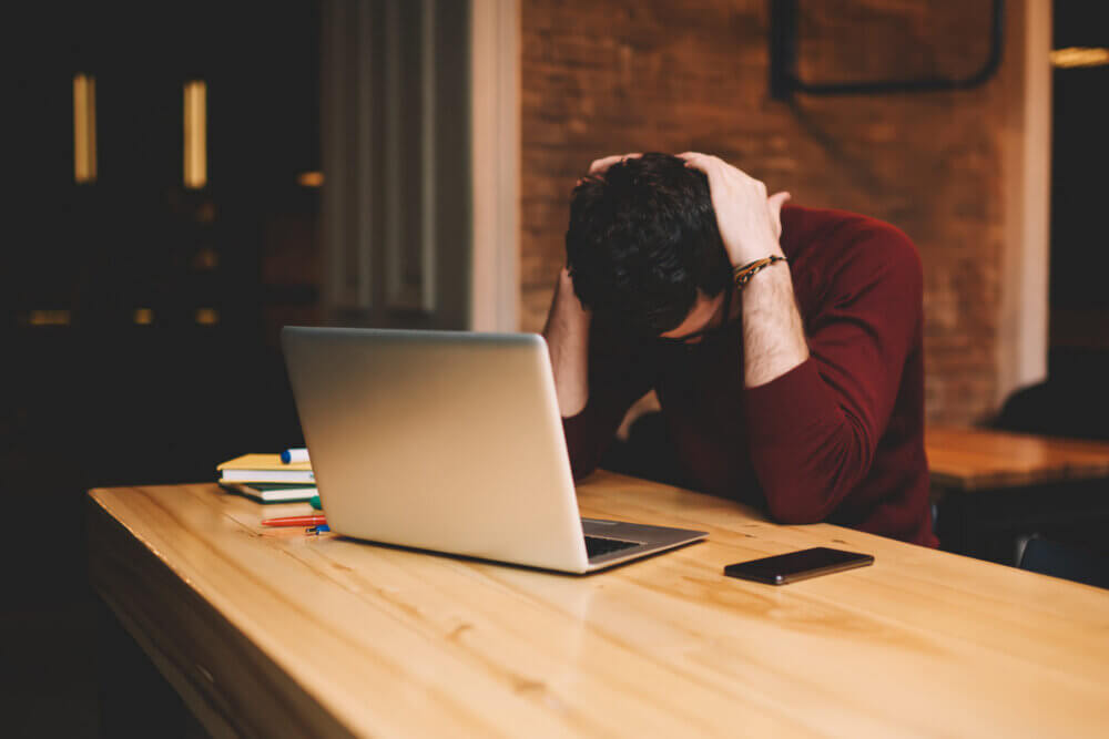 Satressed and worried businessman using laptop computer and free wireless connection to internet during free time in cafe indoors