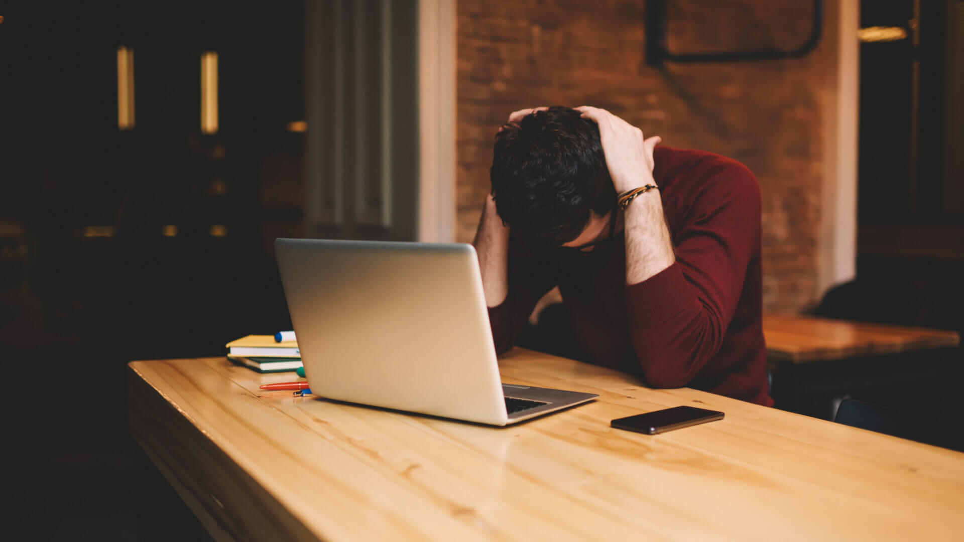 Satressed and worried businessman using laptop computer and free wireless connection to internet during free time in cafe indoors