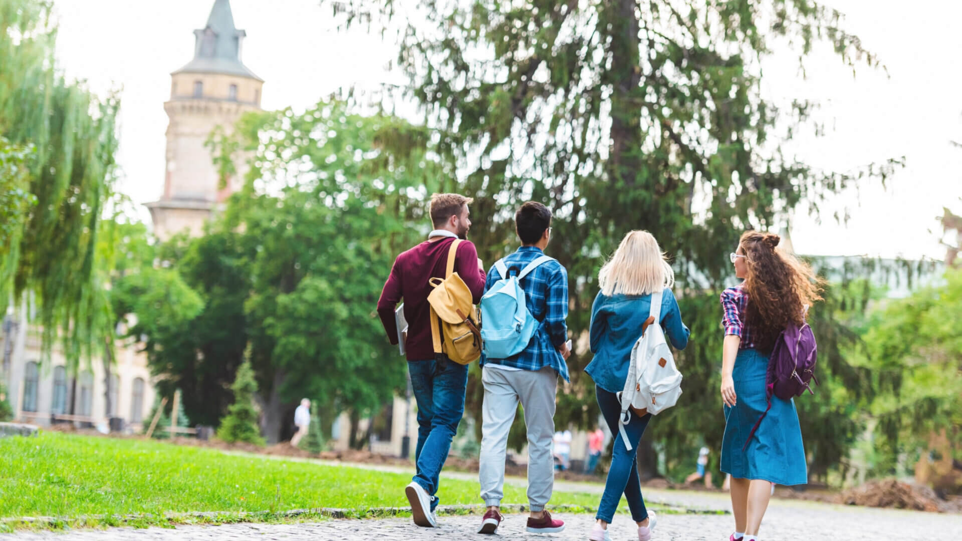 back view of students with backpacks walking on street