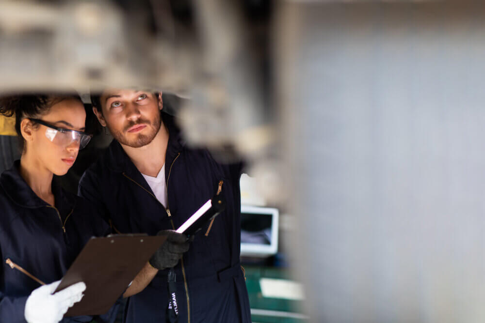 Hispanic Female trainee Mechanics Working Underneath Car Together Car maintenance and auto service garage. Car maintenance and auto service garage concept.