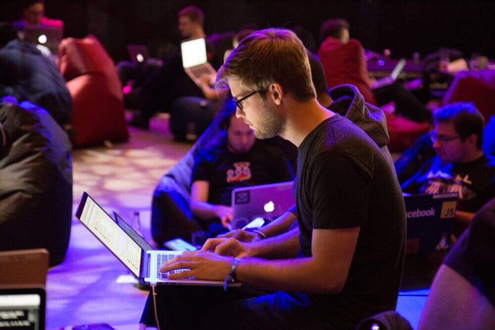 a man sits on a beanbag chair typing on his laptop
