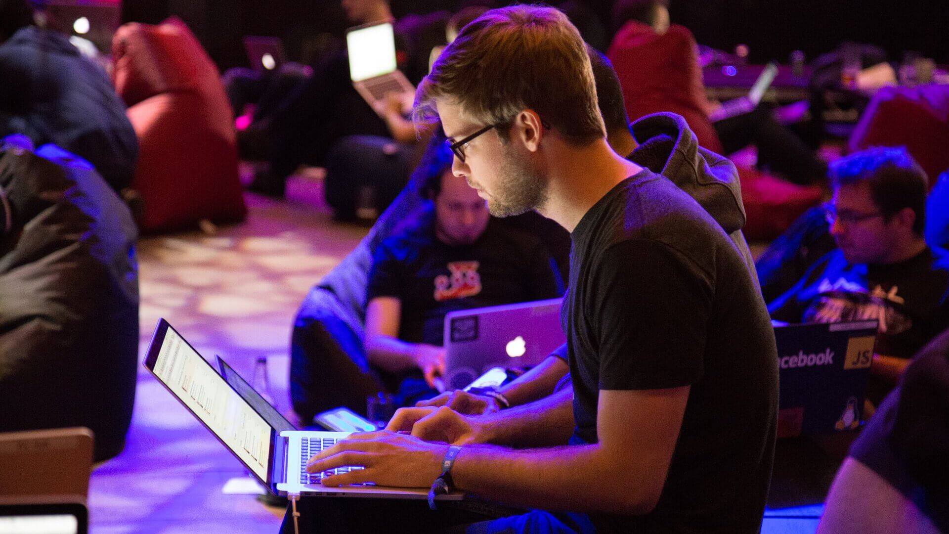 a man sits on a beanbag chair typing on his laptop