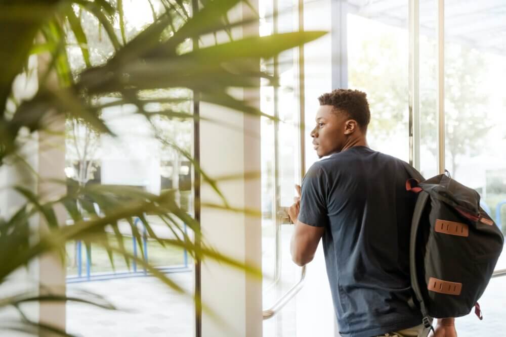 college student walking through doorway with backpack on