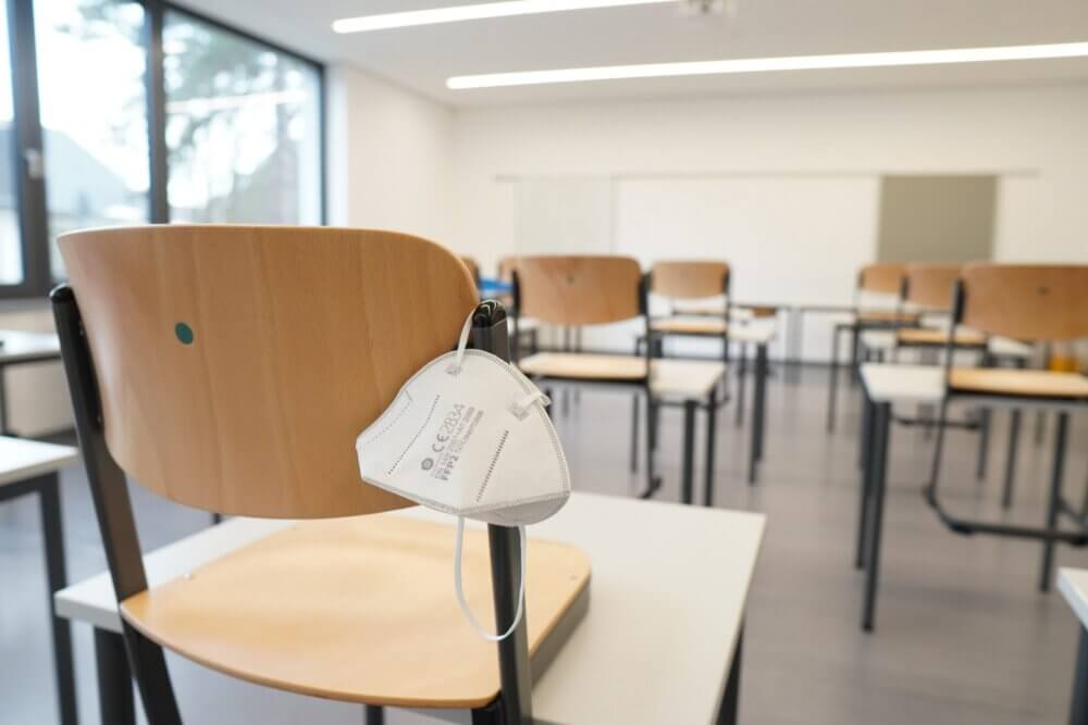 an empty college classroom with n95 masks hanging from the chairs