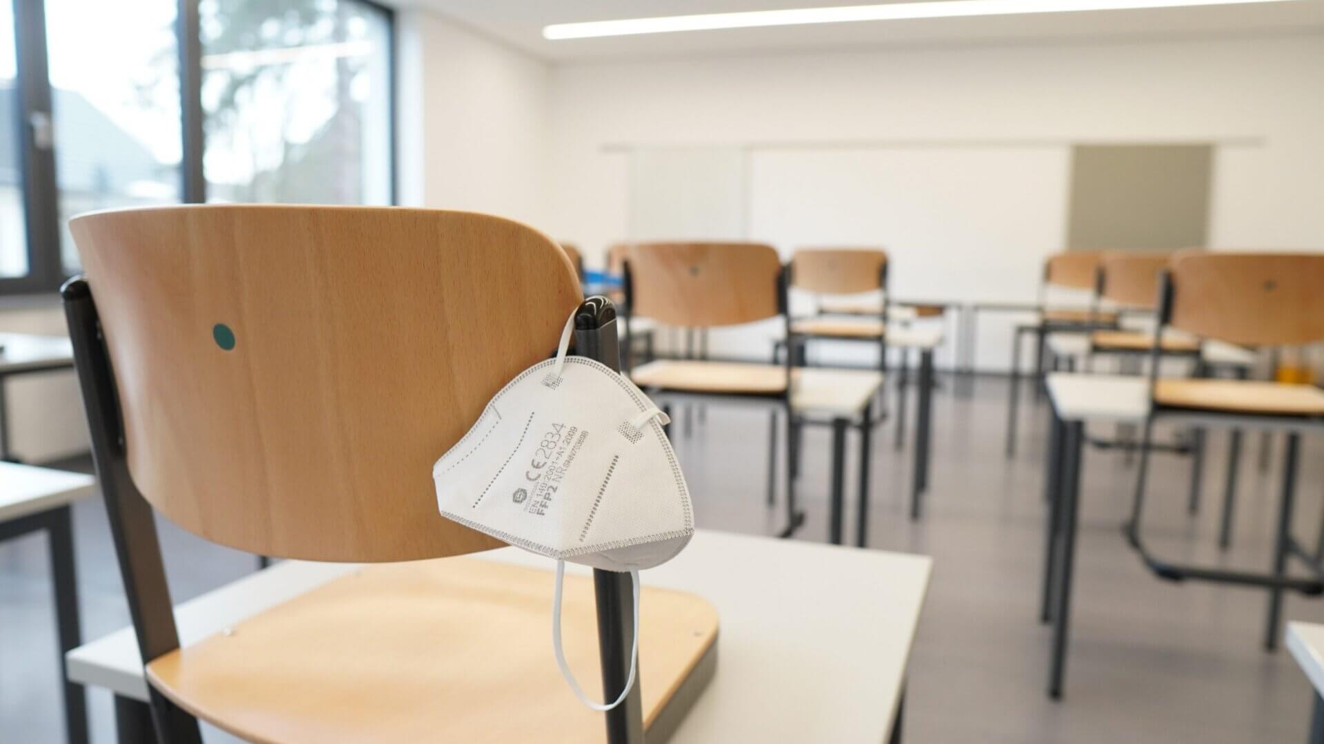 an empty college classroom with n95 masks hanging from the chairs