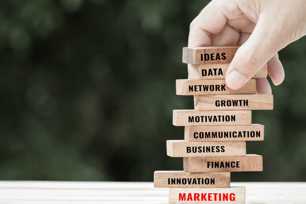 Strategy planning risk in business concept : Businessman placing wooden blocks with letter e.g marketing, finace, business, motivation etc. Ideas for alternative risk in success