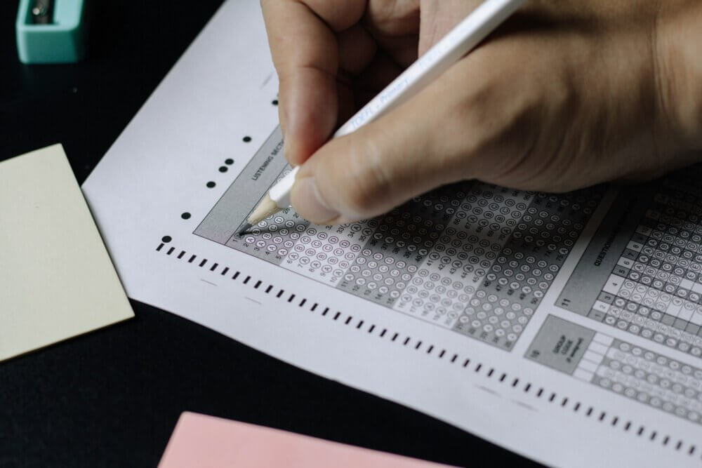 Person filling in multiple choice exam sheet