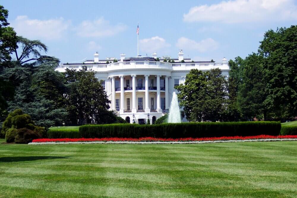 White House on a sunny blue sky day green grass lawn in front yard.