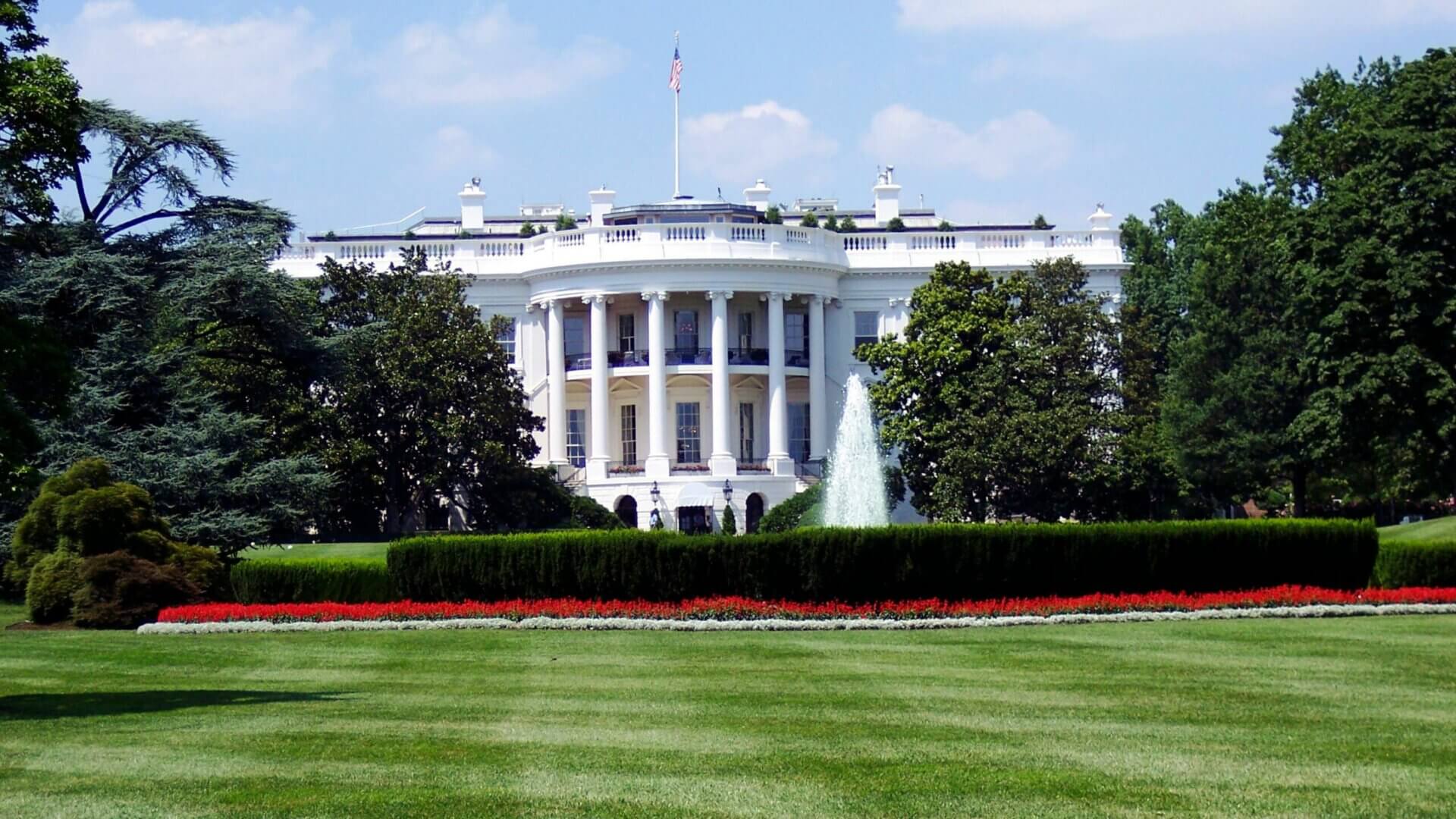 White House on a sunny blue sky day green grass lawn in front yard.