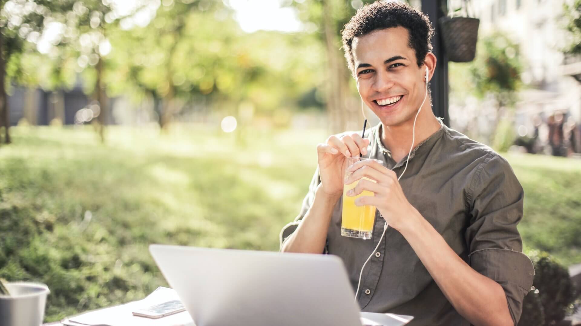 Happy young man drinking lemonade with computer