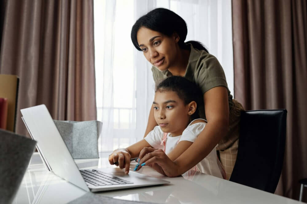 a mom teaching her child at home on a laptop