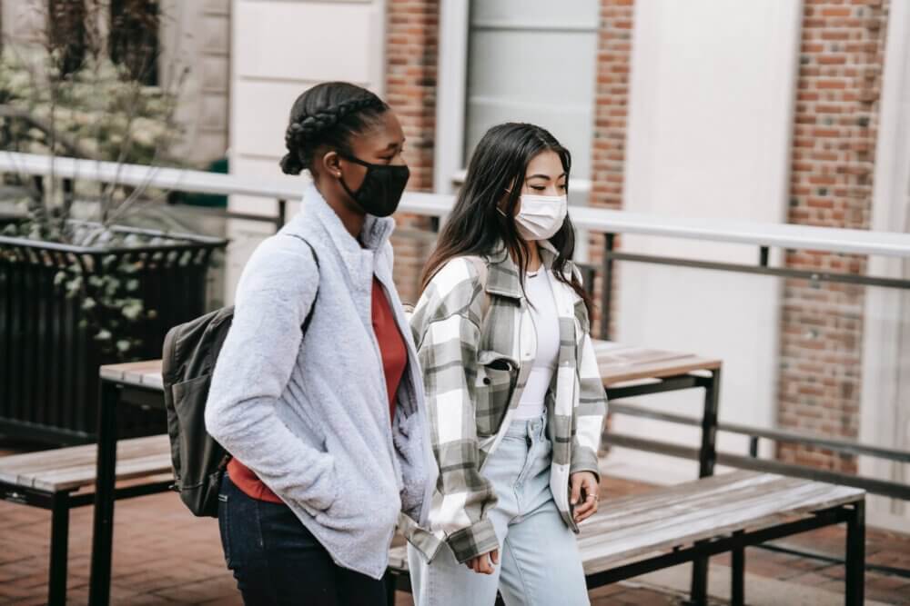 Two college students walking together with masks