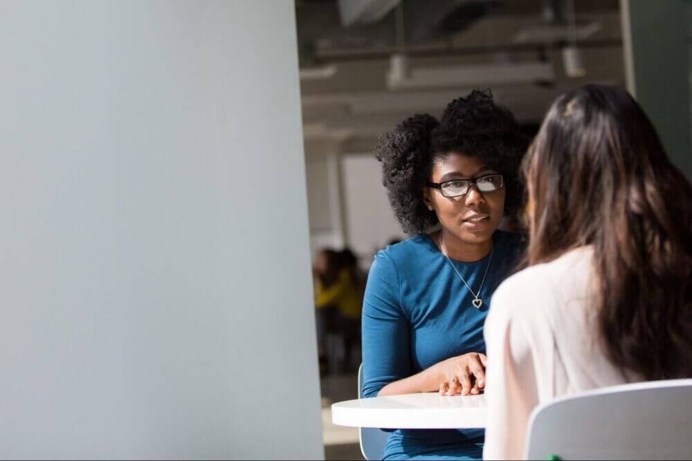 Two women talking to each other at a table
