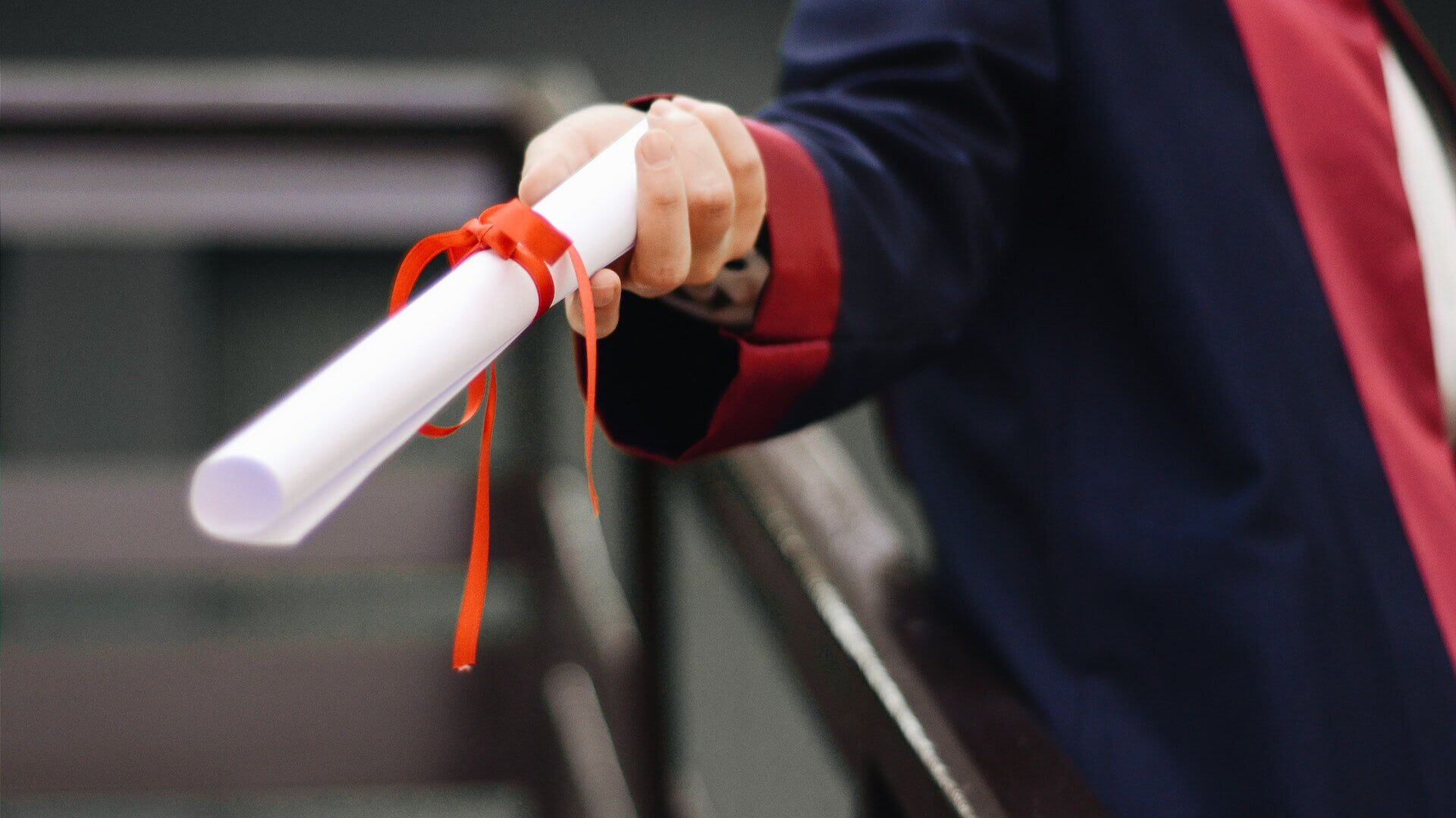 student holding degree wrapped in ribbon