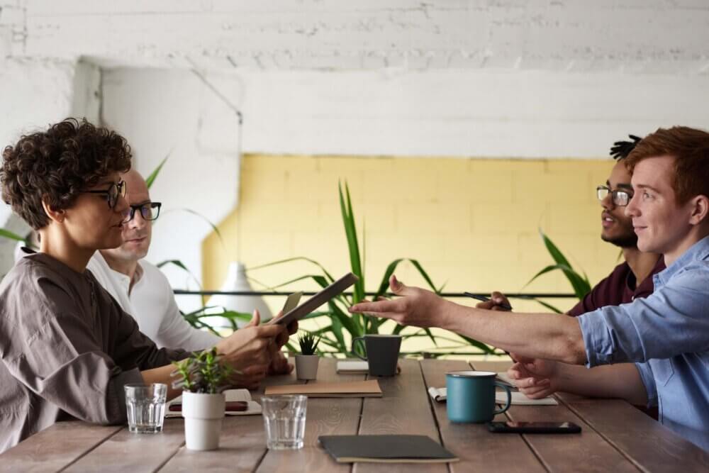four people sitting at a table sharing ideas