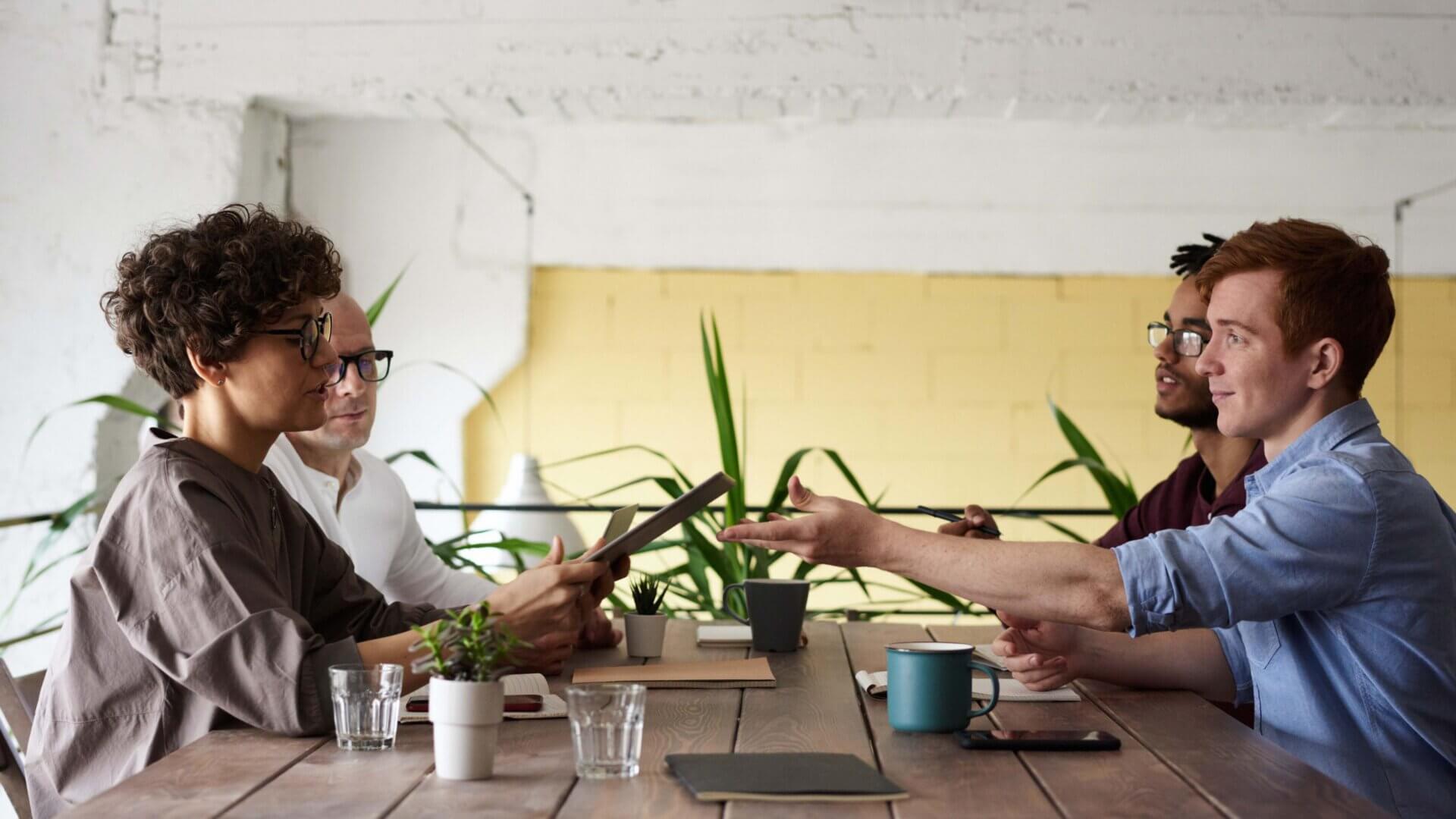 four people sitting at a table sharing ideas