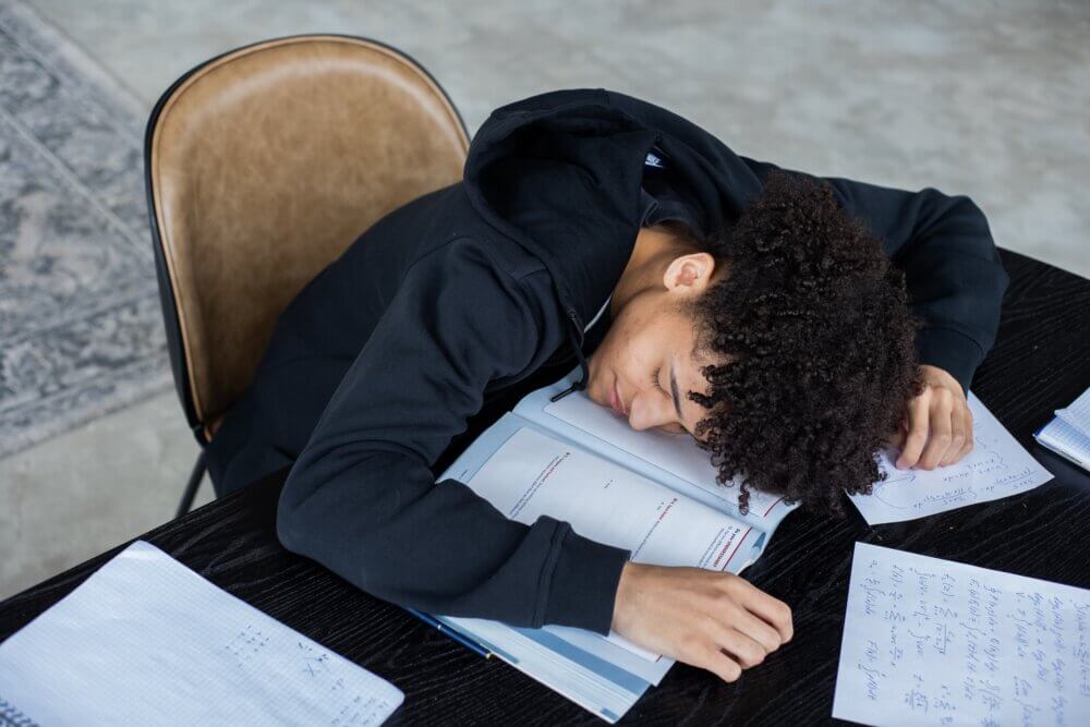 student sleeping on top of school work