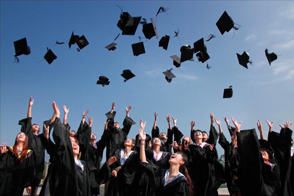 Graduates throwing graduation caps in the air