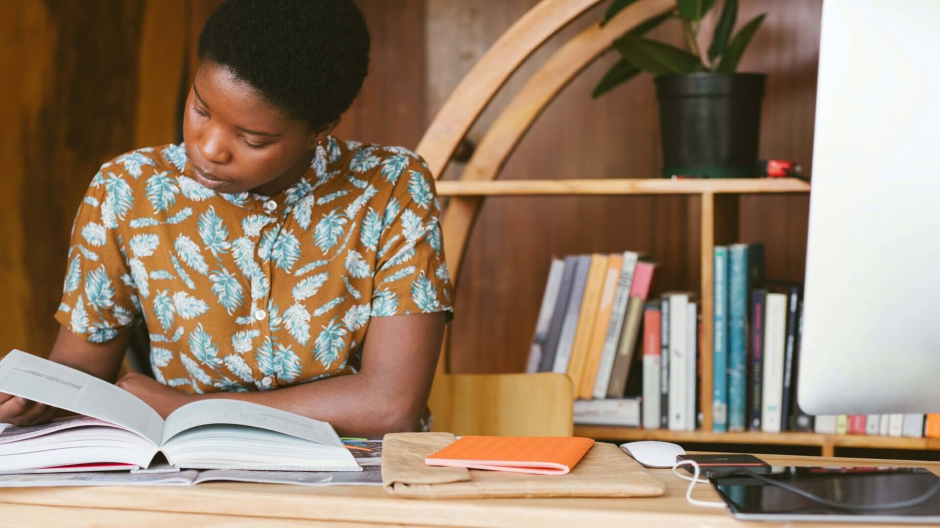 a female college student looks through a textbook while sitting at a desk.