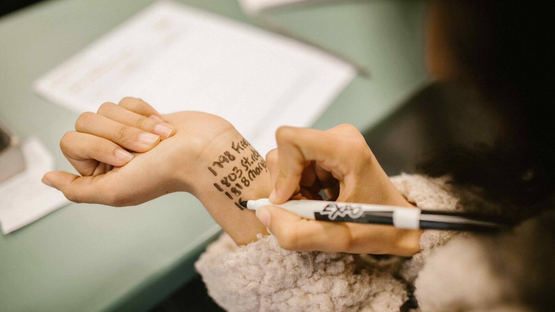 a student writing on her wrist with a sharpie