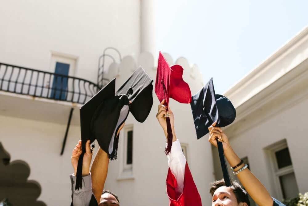 graduation caps being held in the air