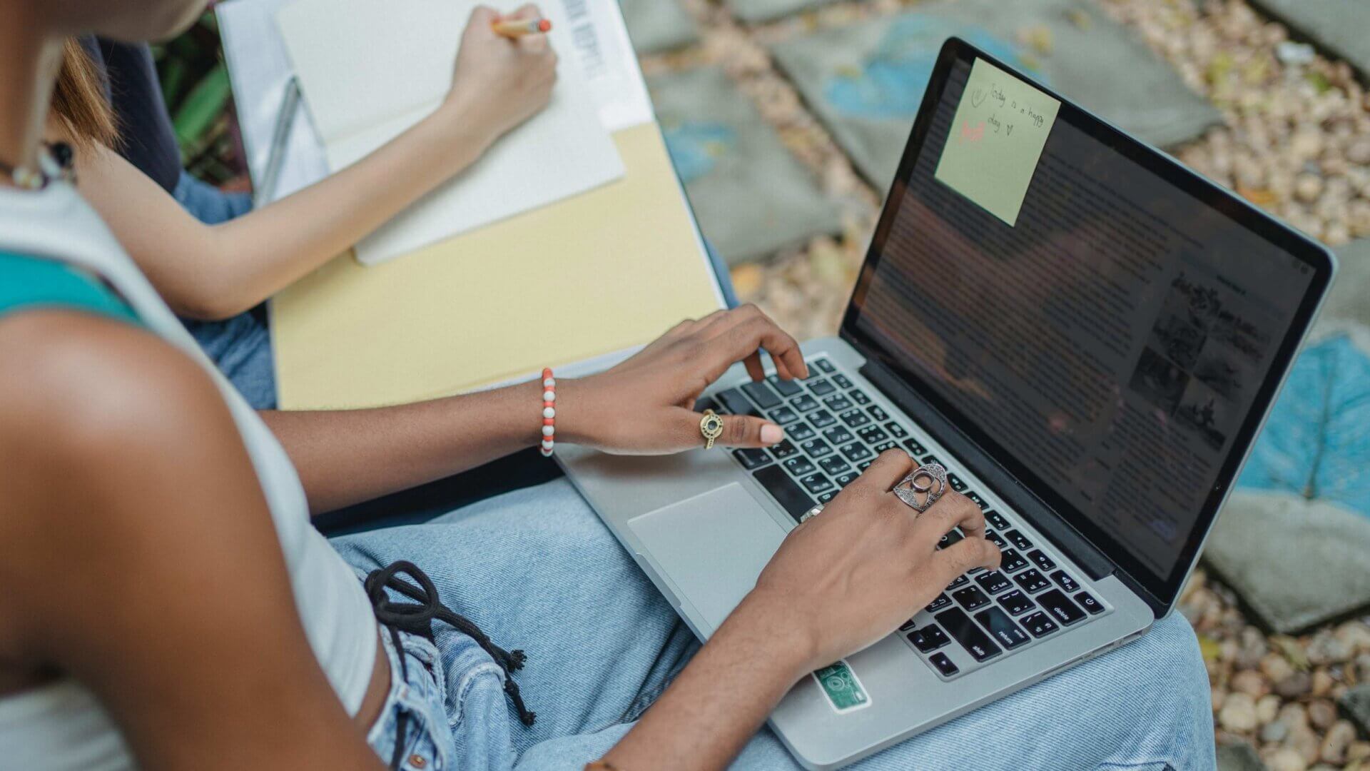 a student types on a laptop with a post-it note attached to the screen