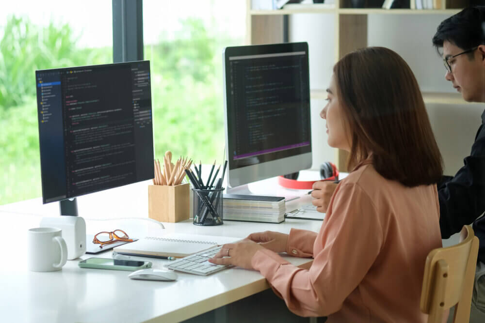 Side view of female programmer working with computer at modern office. Developing programming.