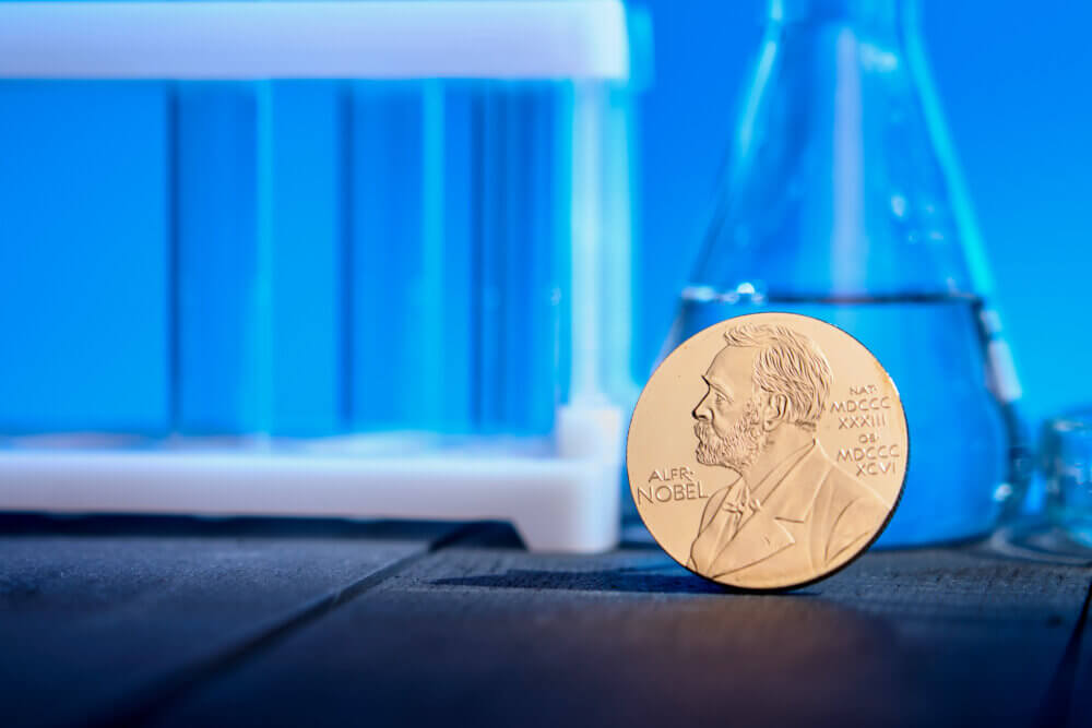 Nobel award against backdrop of chemical test tubes on blue background.