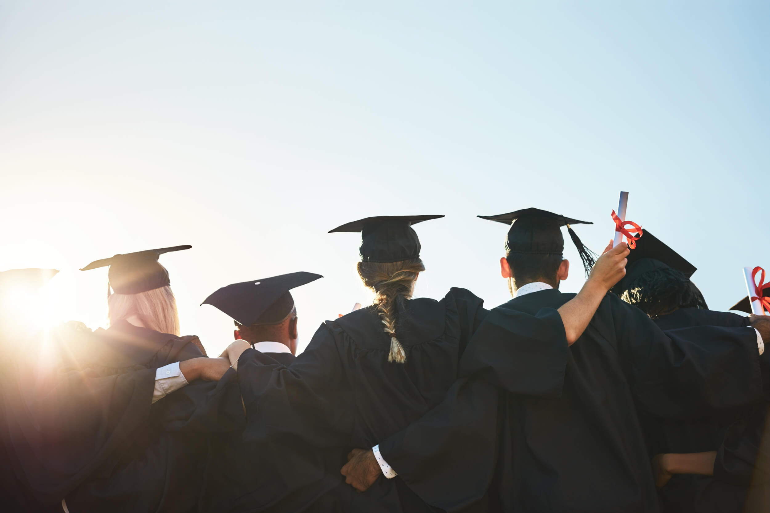 Group of graduates in cap and gown posing for a picture.