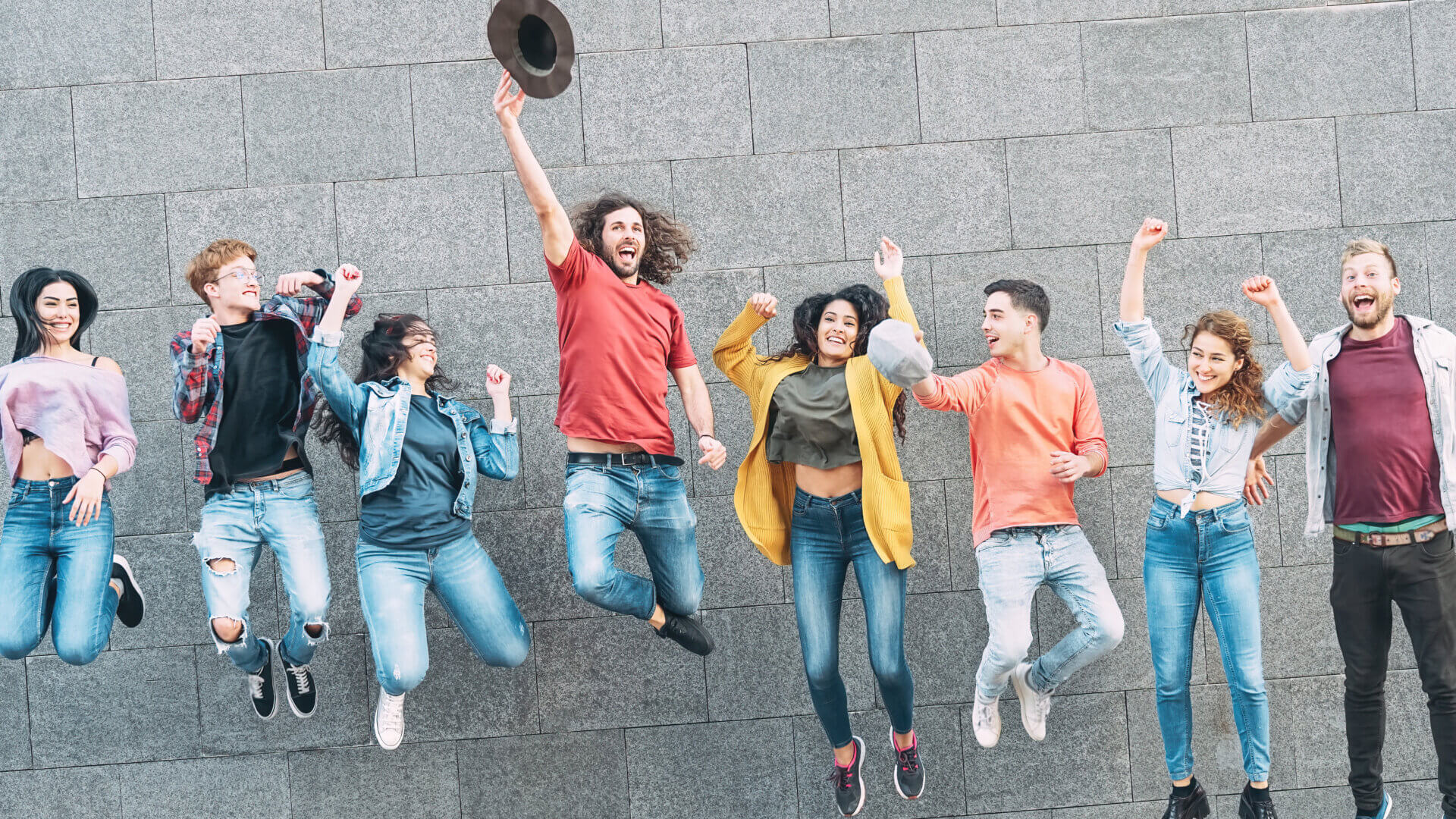 Group of young people jumping together outdoors.