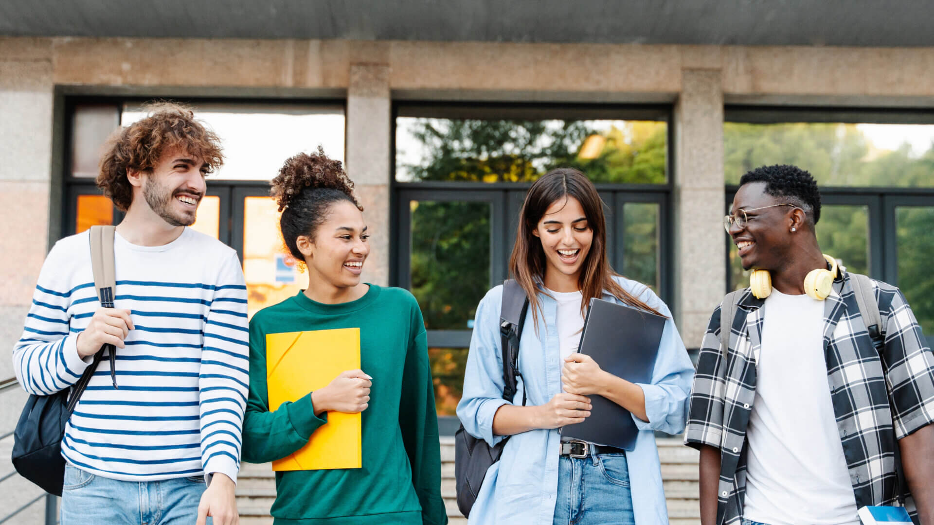 Happy students walking together on university campus, chatting and laughing outdoors after classes