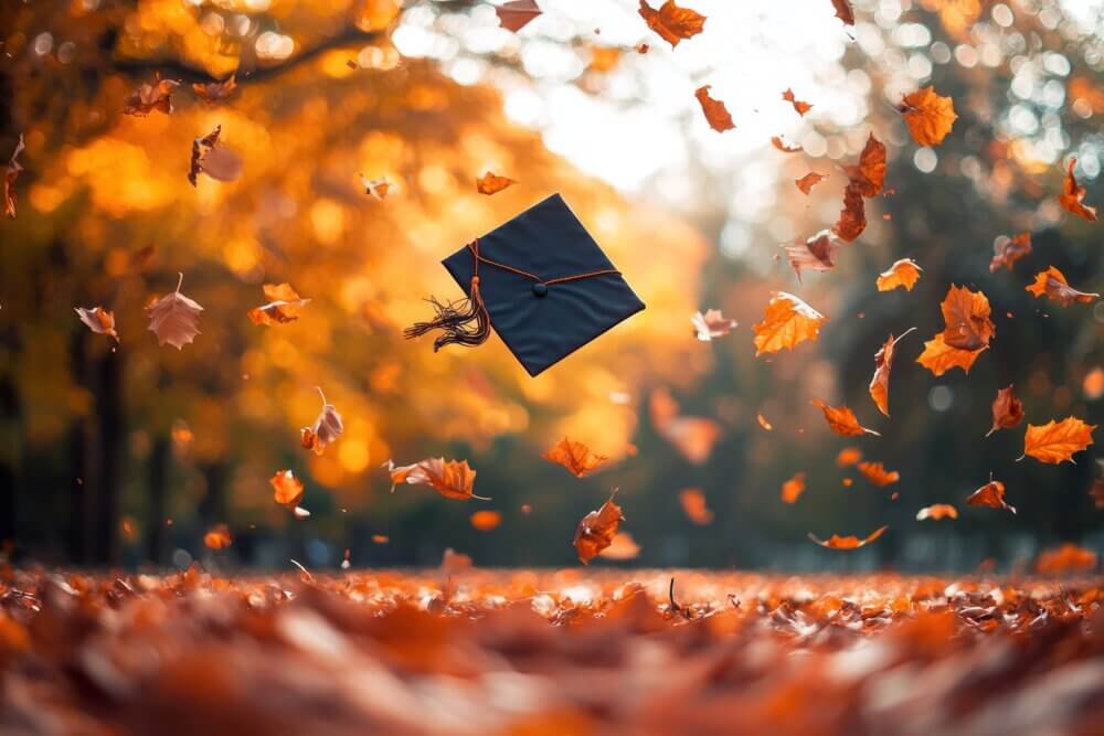 Autumn Graduation Cap Floating in Falling Leaves.