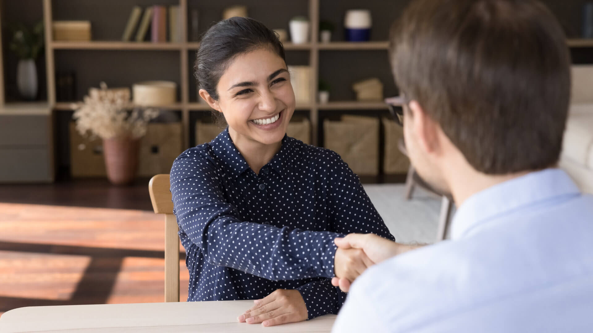 Woman shaking hand of person interviewing her for role at company.